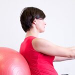 Woman in Red Shirt Sitting on Fitness Equipment